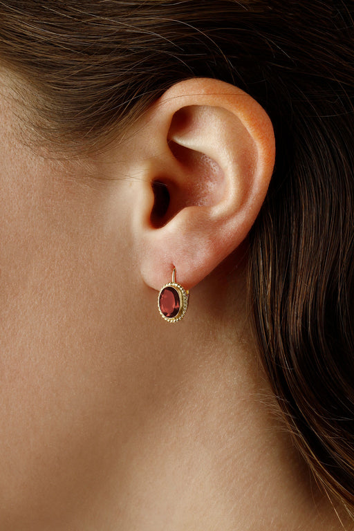 14 karat yellow gold oval garnet lever back pierced drop earrings with twist bezel on model