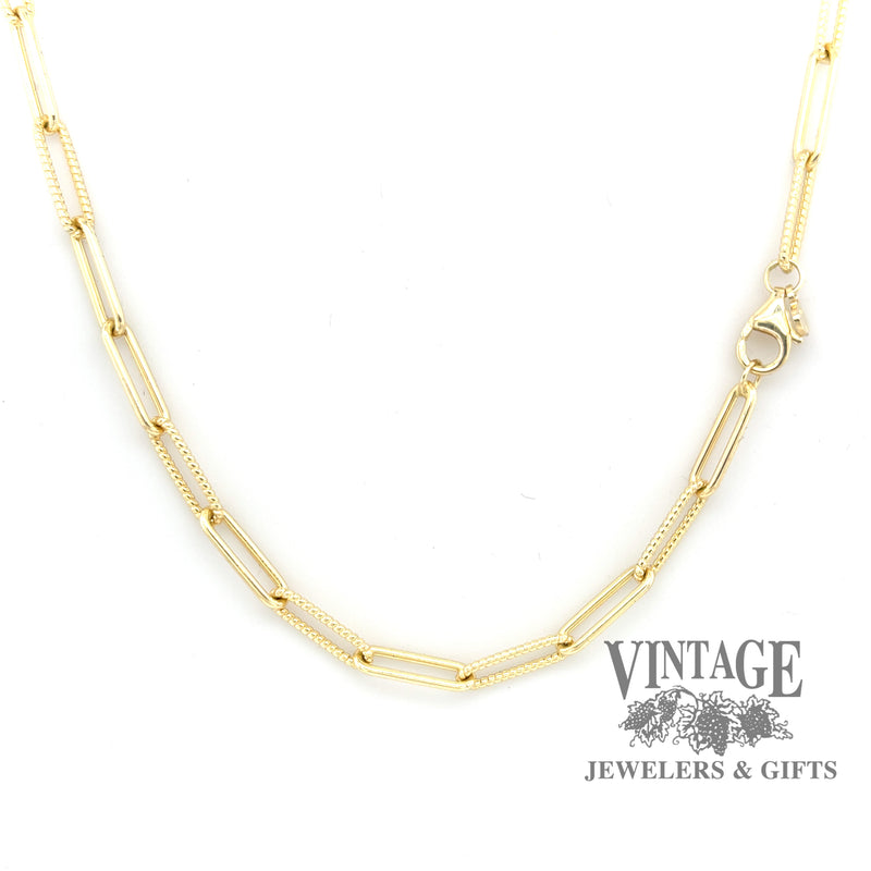 Paperclip-link chain showing alternating smooth and textured 14 karat yellow gold links, secured with a lobster claw clasp.