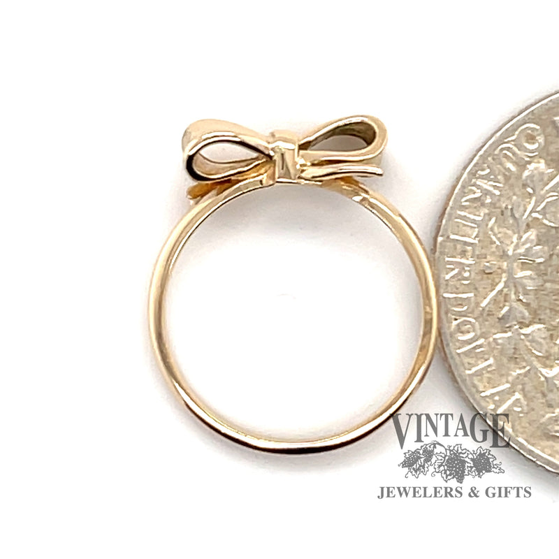 14 karat yellow gold ribbon bow design ring, next to quarter for scale