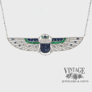 Revolving video of 18 karat white gold Egyptian revival sapphire, emerald and diamond scarab necklace