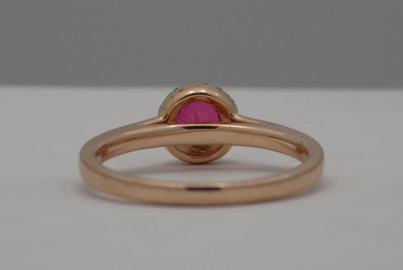 Rose gold natural round ruby with diamond halo ring.