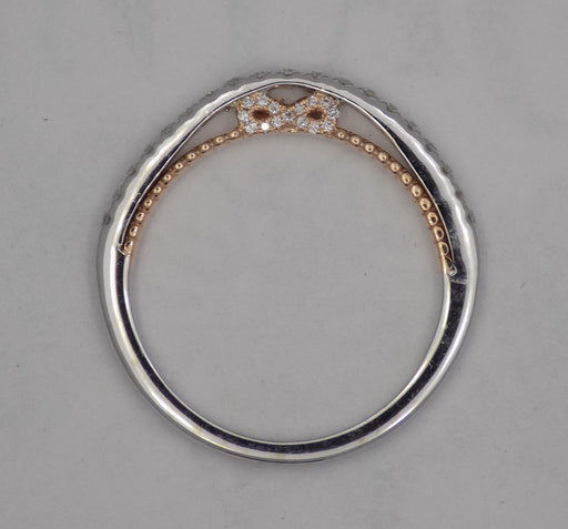 14 karat two-tone, white and rose gold diamond wedding band with infinity design, side view through finger.