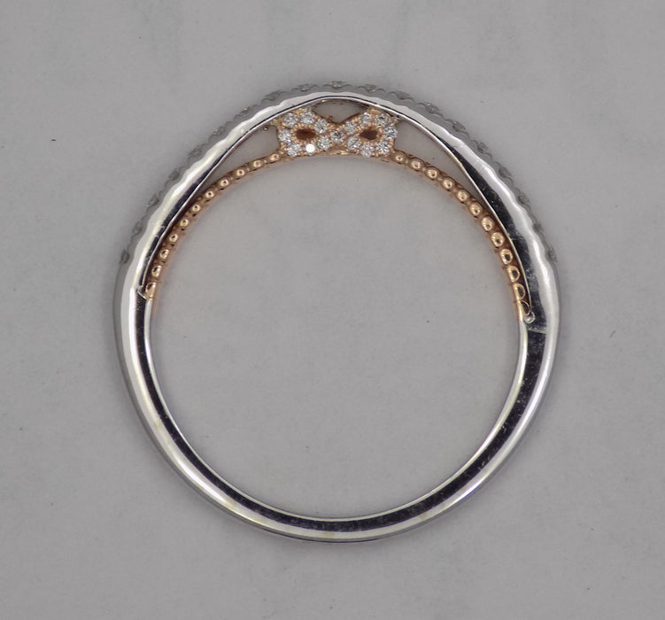 14 karat two-tone, white and rose gold diamond wedding band with infinity design, side view through finger.