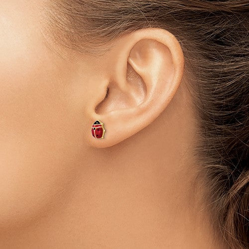 14 karat yellow gold ladybug stud earrings with red and black enameling, on model