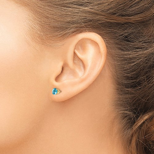 Model wearing 14 karat yellow gold Blue Topaz 5mm stud Earrings