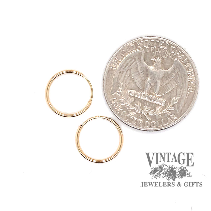 14 karat yellow gold mini endless hoop earrings, shown with quarter for size reference