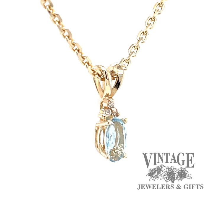 Side view of 14 karat yellow gold pendant with natural oval shaped aquamarine and diamond accents