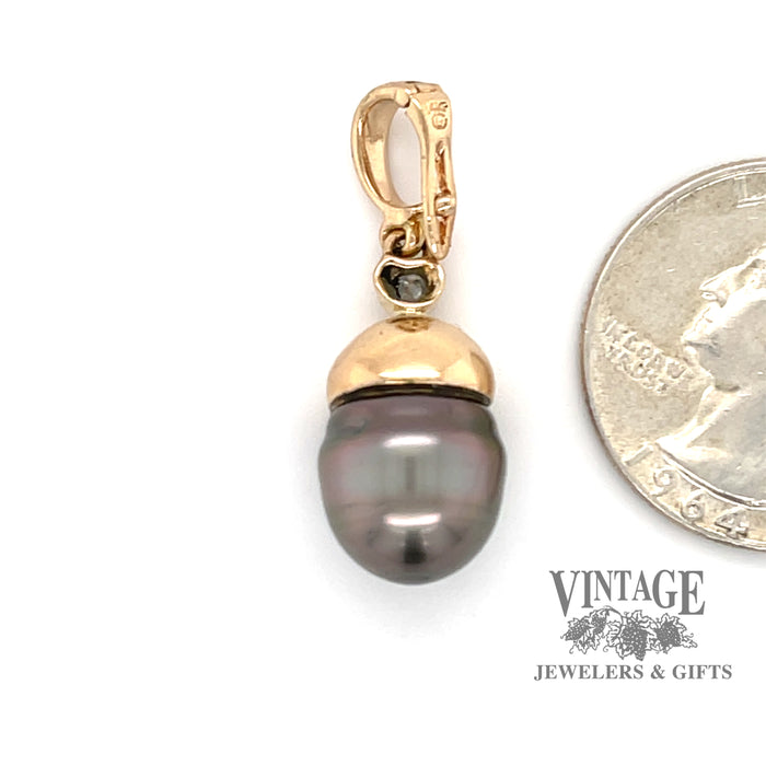 Tahitian pearl and diamond enhancer pendant next to quarter for scale