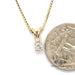 14 karat yellow gold .23 carat diamond pendant with small accent diamond, shown with quarter for size reference