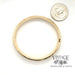 embossed floral motif 14 karat yellow gold bangle bracelet, shown with quarter for size reference