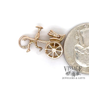 Rickshaw 14k yellow gold charm, shown alongside a quarter for size reference