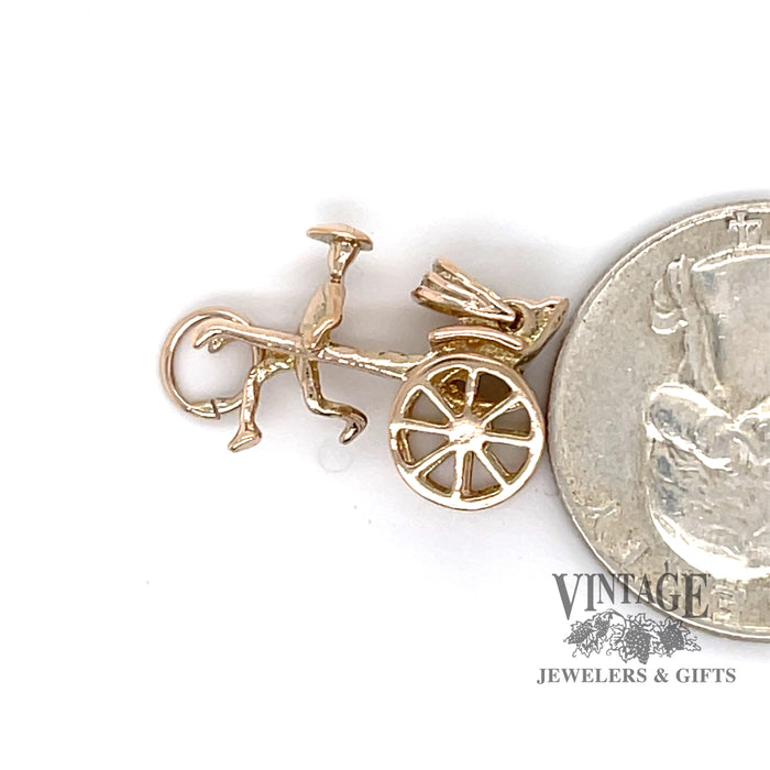 Rickshaw 14k yellow gold charm, shown alongside a quarter for size reference