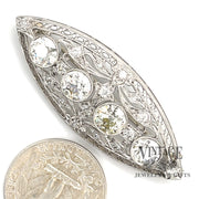 Antique Edwardian platinum and diamond brooch next to quarter for scale