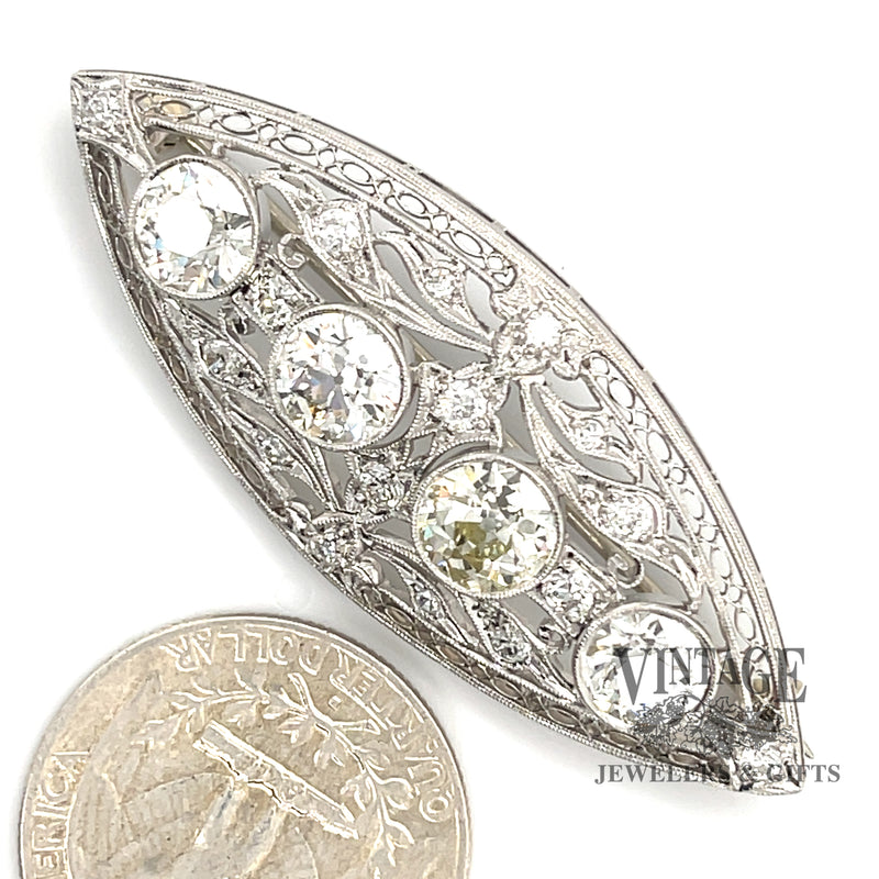 Antique Edwardian platinum and diamond brooch next to quarter for scale