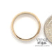 14 karat yellow gold four leaf clover pattern band ring, shown with quarter for size reference