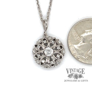 Estate 14 karat white gold round floral design diamond pendant, shown with quarter for size reference